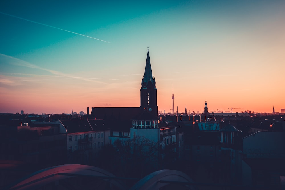 a view of a city with a church steeple at sunset