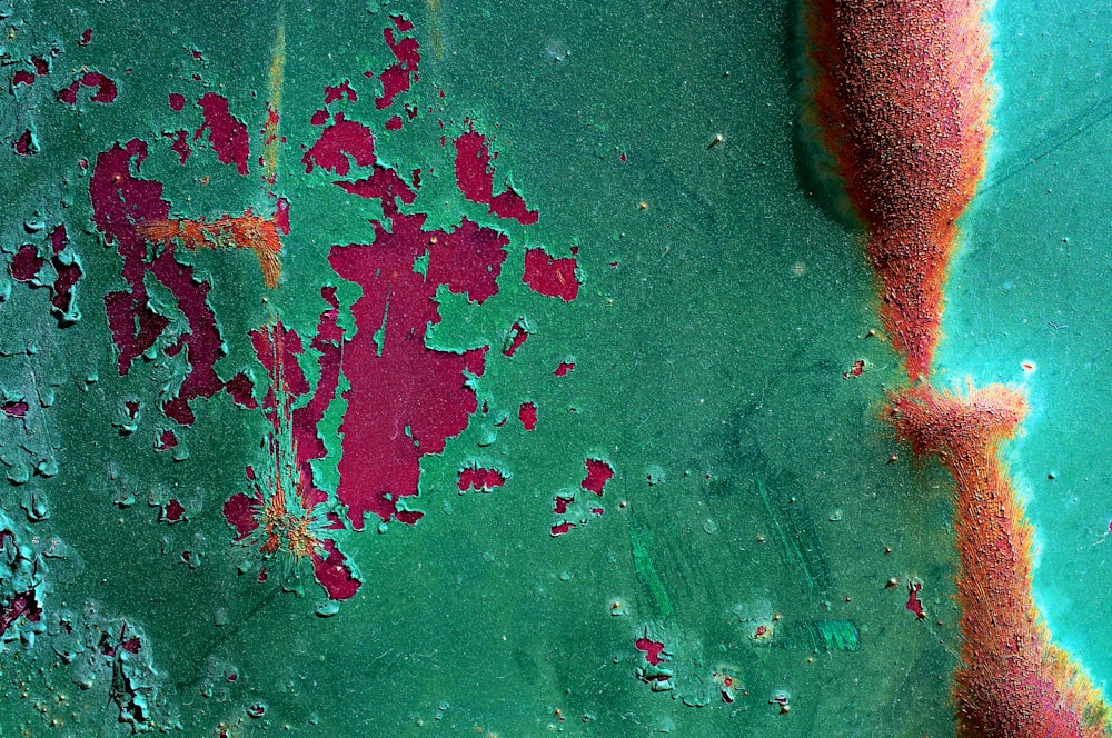 a close up of a green surface with red paint