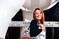 A smiling woman holding a personalized tote bag with a floral design.