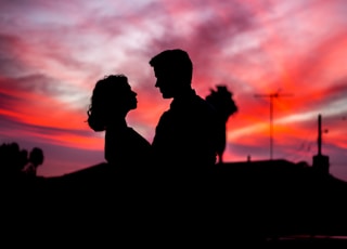 silhouette of man and woman facing each other during golden hour