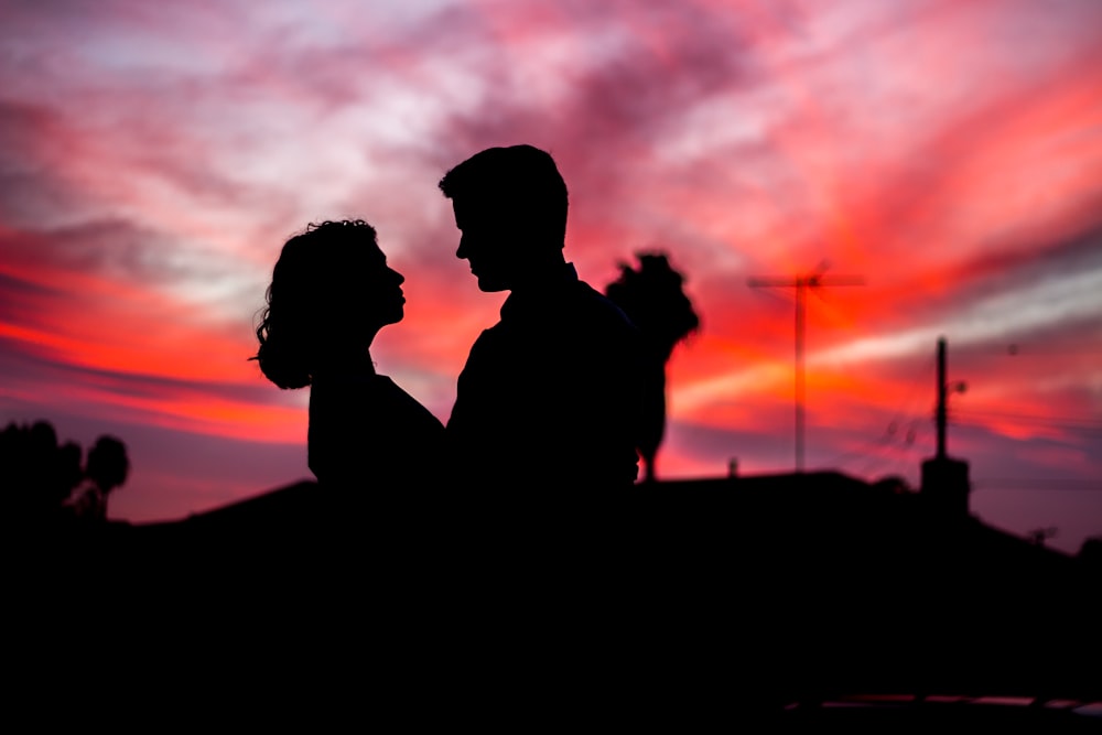 silueta de hombre y mujer uno frente al otro durante la hora dorada