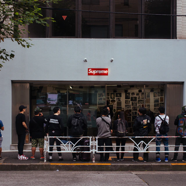 People waiting in a line along a fence outside the Supreme store in Shibuya, Tokyo, on a drop day