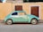 teal Volkswagen Beetle parked near brown house