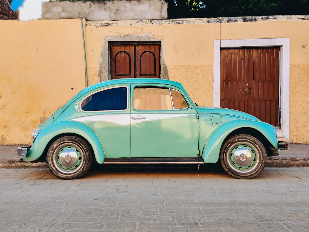 teal Volkswagen Beetle parked near brown house