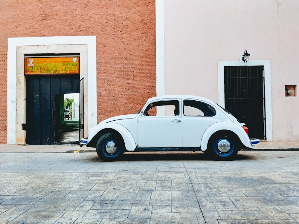 Escarabajo Volkswagen blanco estacionado cerca de un edificio durante el día