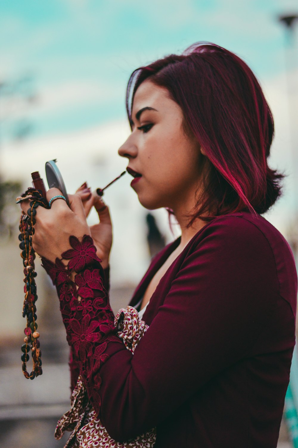 tilt shift lens photography of woman pouring red lipstick on her lips