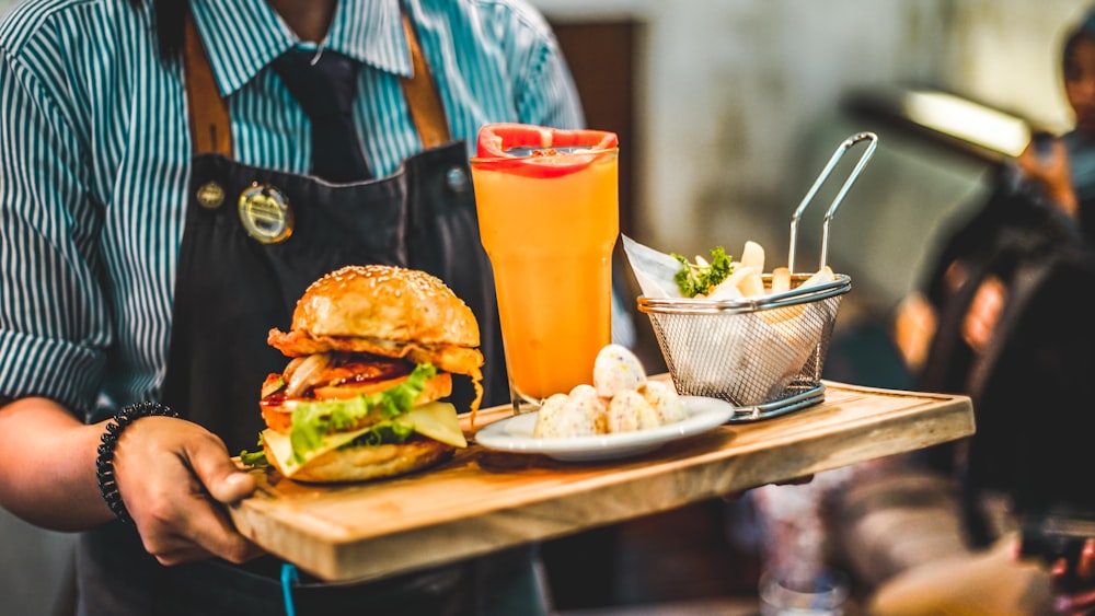 person serving burger with pitcher of juice