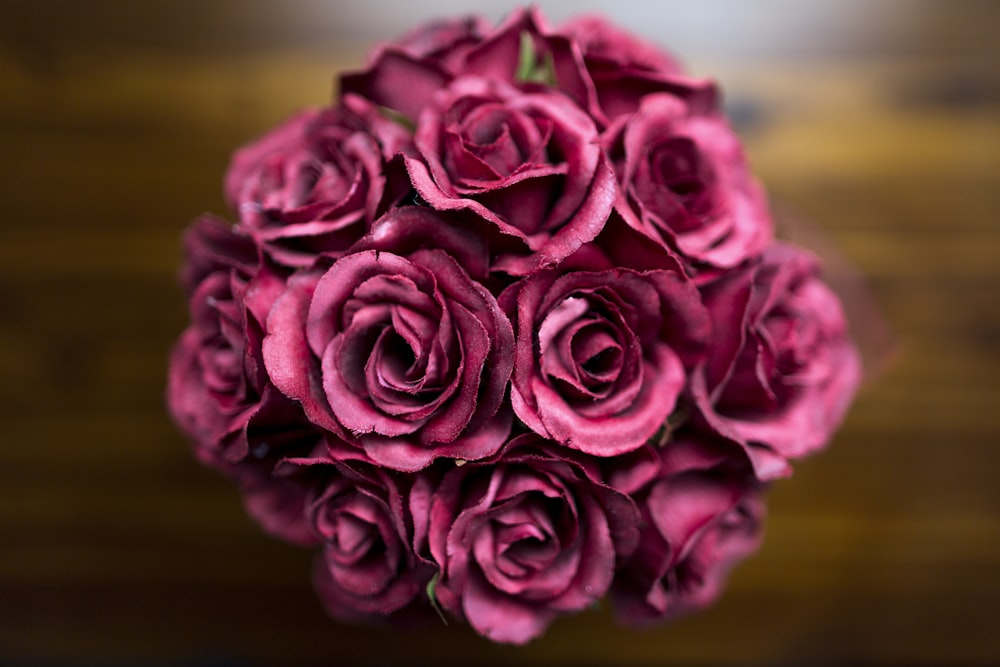 a bouquet of pink roses sitting on top of a wooden table