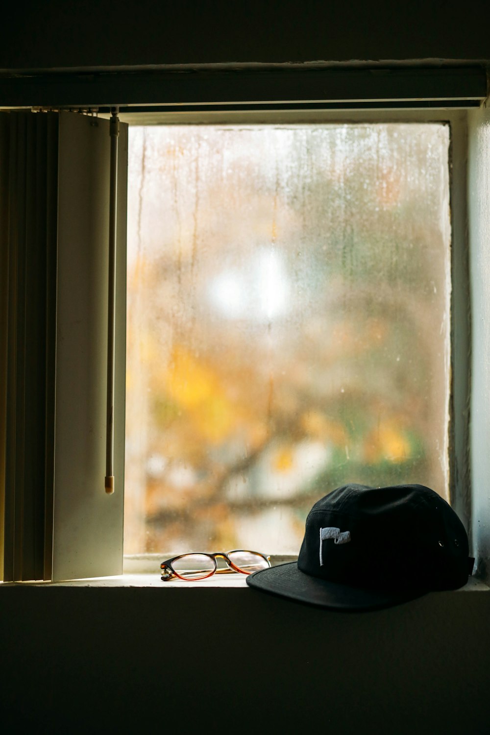 black cap and eyeglasses in front of window