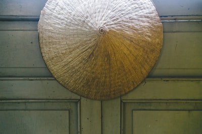 Handcrafted paddy torana hanging on a rustic wooden door, showcasing un-husked rice grains and natural fibers.