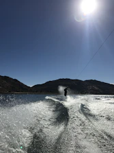 A wakeboarder jumping high above sparkling blue water on a sunny day.