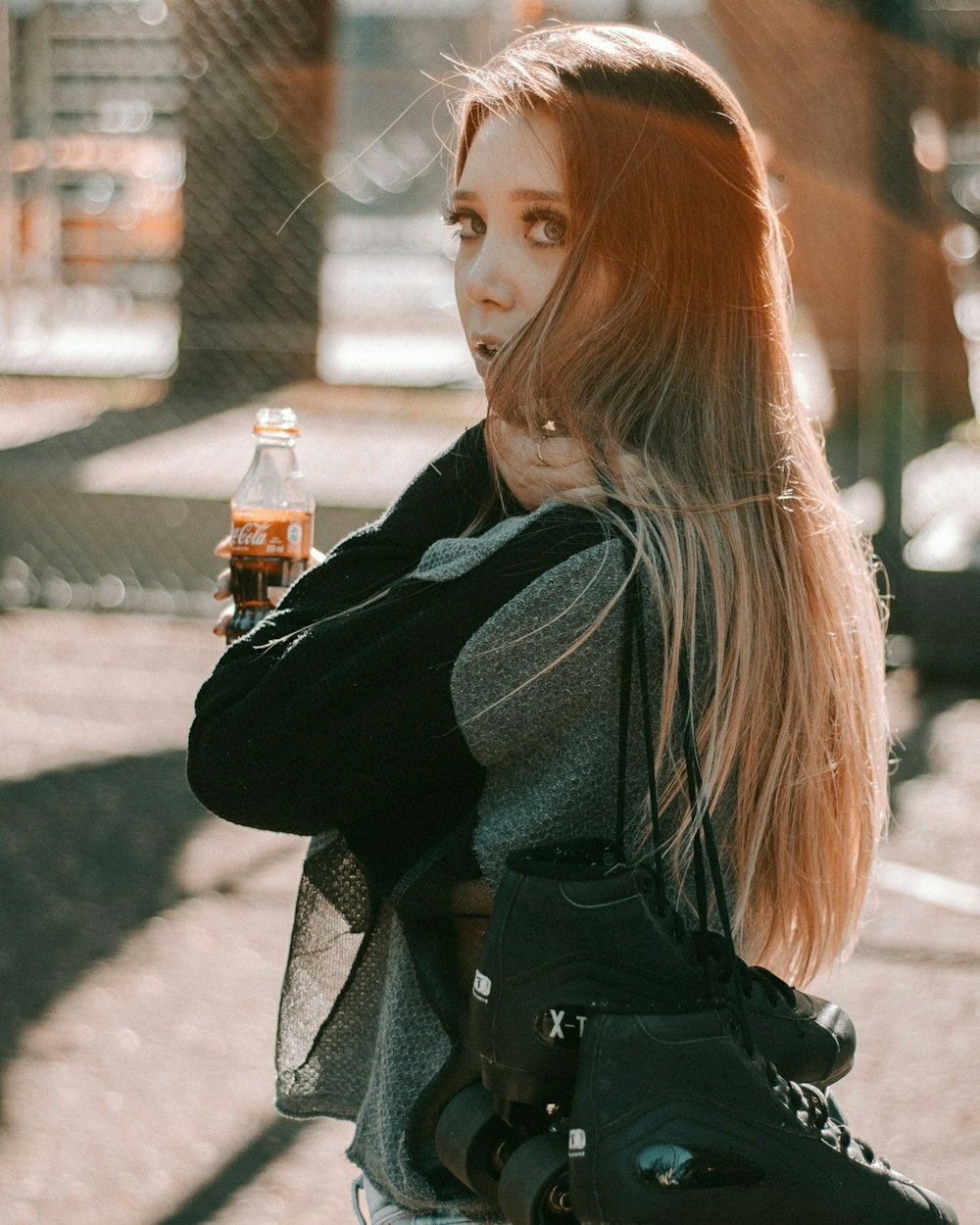 Mujer con chaqueta negra y gris sosteniendo una botella de Coca-Cola