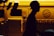 A silhouette of a person wearing a cap is prominently featured against the backdrop of a brightly lit yellow service vehicle with the word 'ROSEG' partially visible and a globe logo. The contrast creates a dramatic interplay between light and dark.