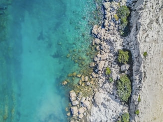 high-angle photo of boulders near clear body of water