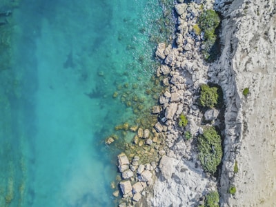high-angle photo of boulders near clear body of water