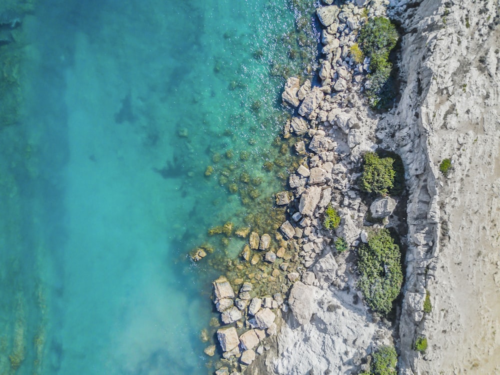 high-angle photo of boulders near clear body of water