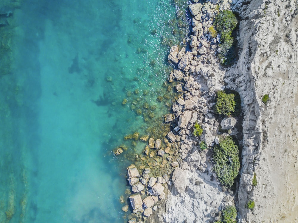 Foto de ángulo alto de rocas cerca de un cuerpo de agua claro