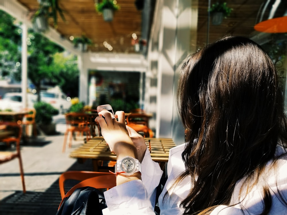 woman using phone near brown table