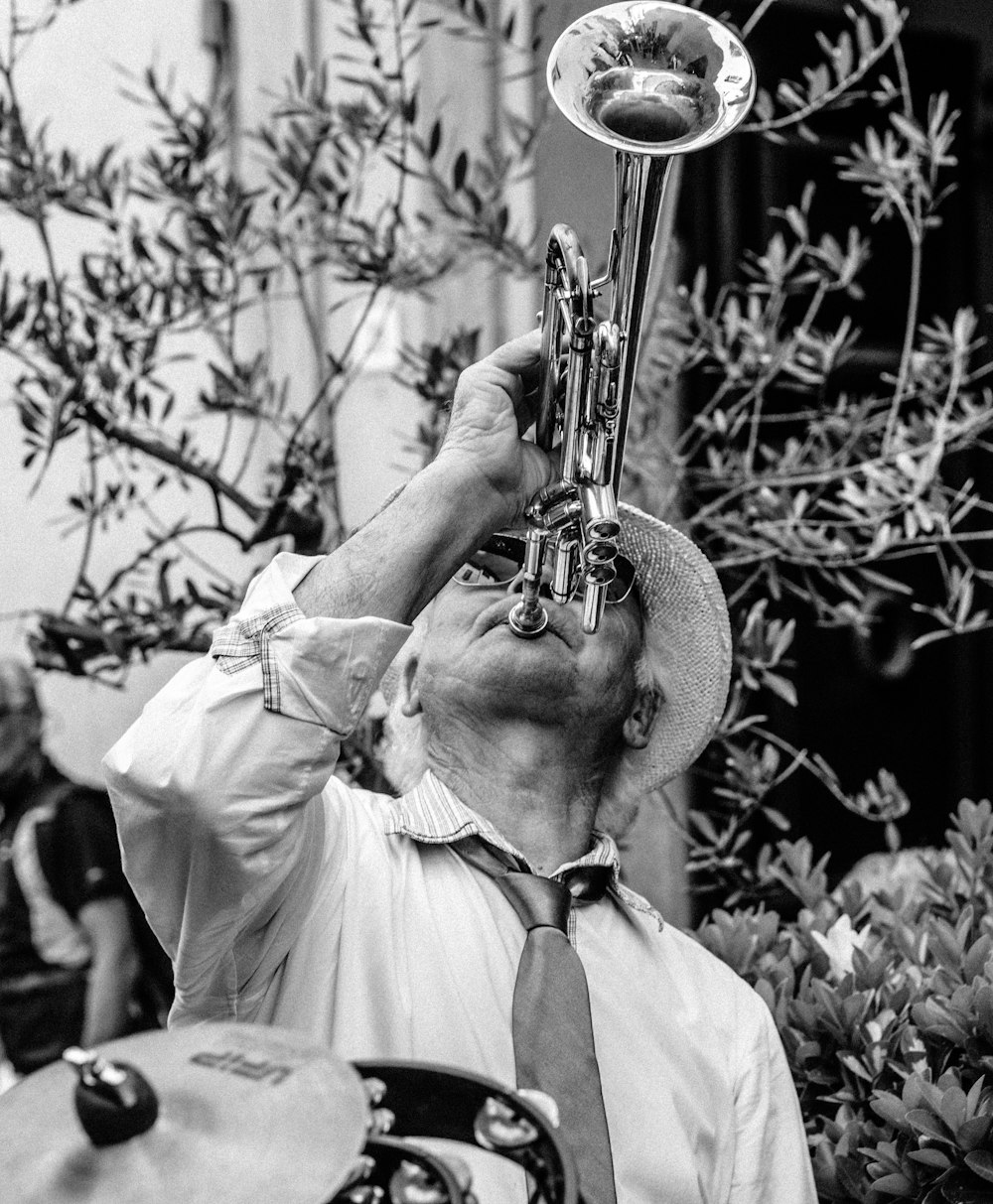 fotografia in scala di grigi di un uomo che suona la tromba