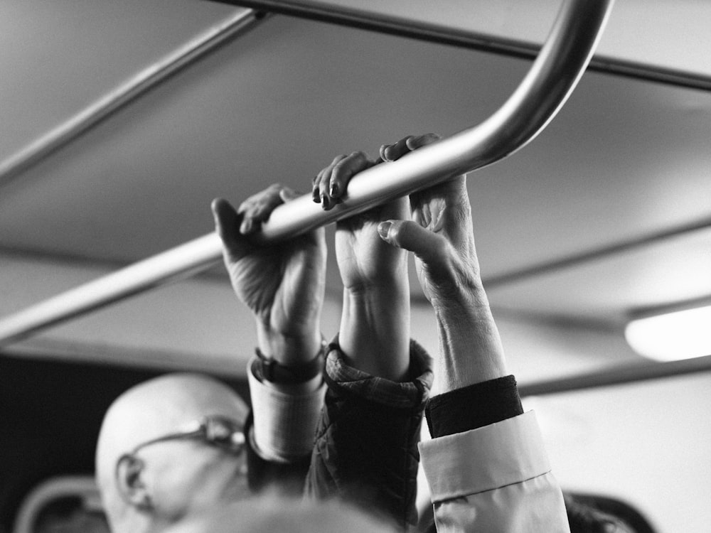 grayscale shot of people's hands on steel bar