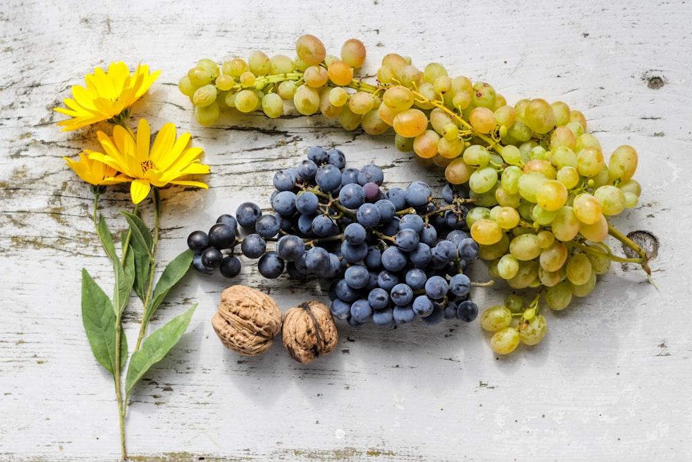 grapes by nut and daisy flower on table