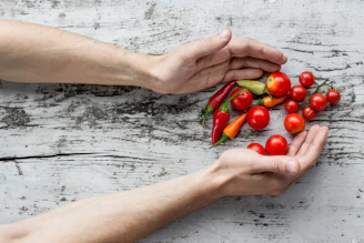 Close-up of hands gently holding fresh herbs and colorful fruits displayed on a kitchen table.