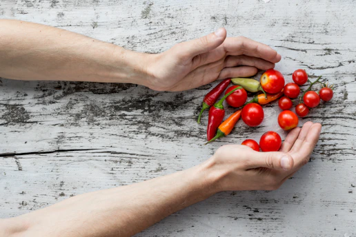 Close-up of hands gently holding fresh herbs and colorful fruits displayed on a kitchen table.