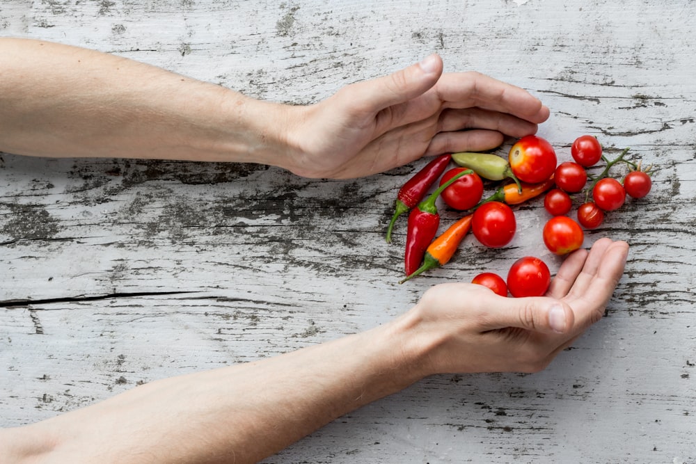 person hand's about to get cherry tomatoes and bell peppers