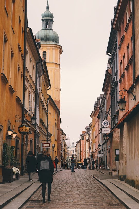 person walking on street near gothic building in Sigismund's Column Poland