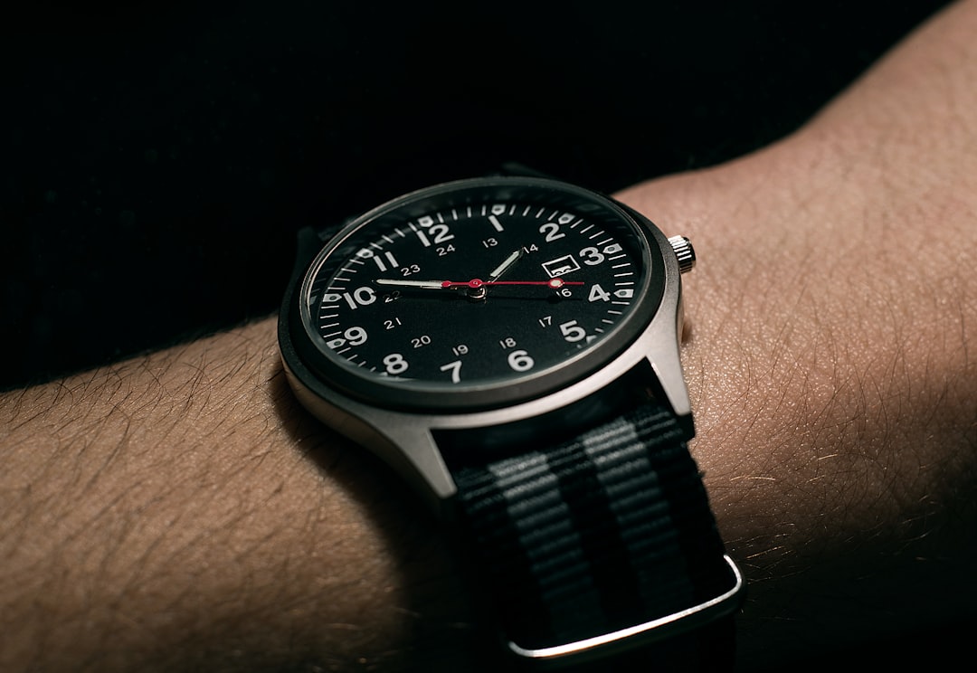 man wears black analog watch with black woven nylon strap