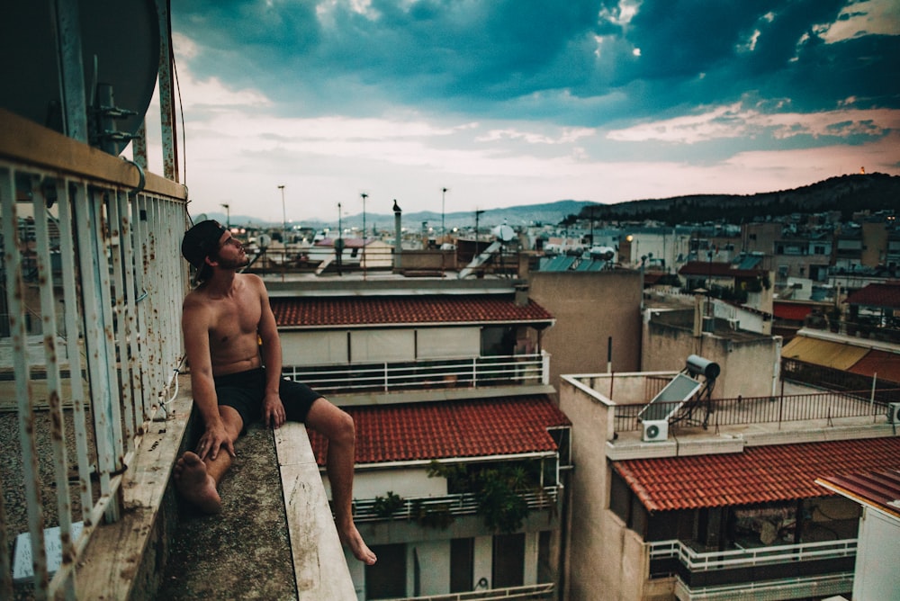 person sitting on the edge of building during daytime