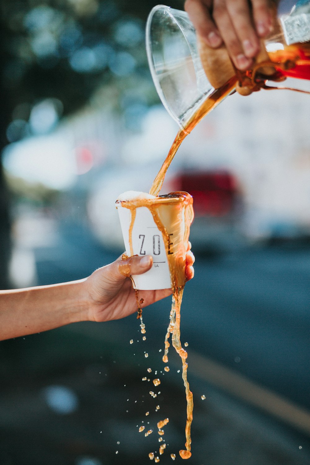 person holding white ZOE brand paper cup