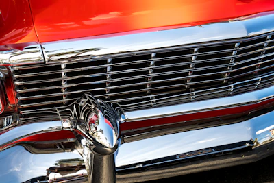 Close-up of a shiny chrome grill reflecting pink and blue neon hues.