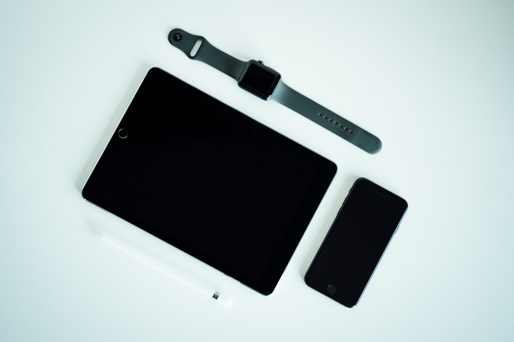 iPad negro, iPhone posterior a 2017 y funda de aluminio negro Apple Watch con correa deportiva gris