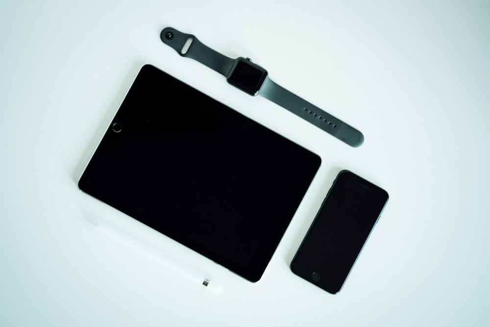 black iPad, post-2017 iPhone, and black aluminum case Apple Watch with gray Sport Band