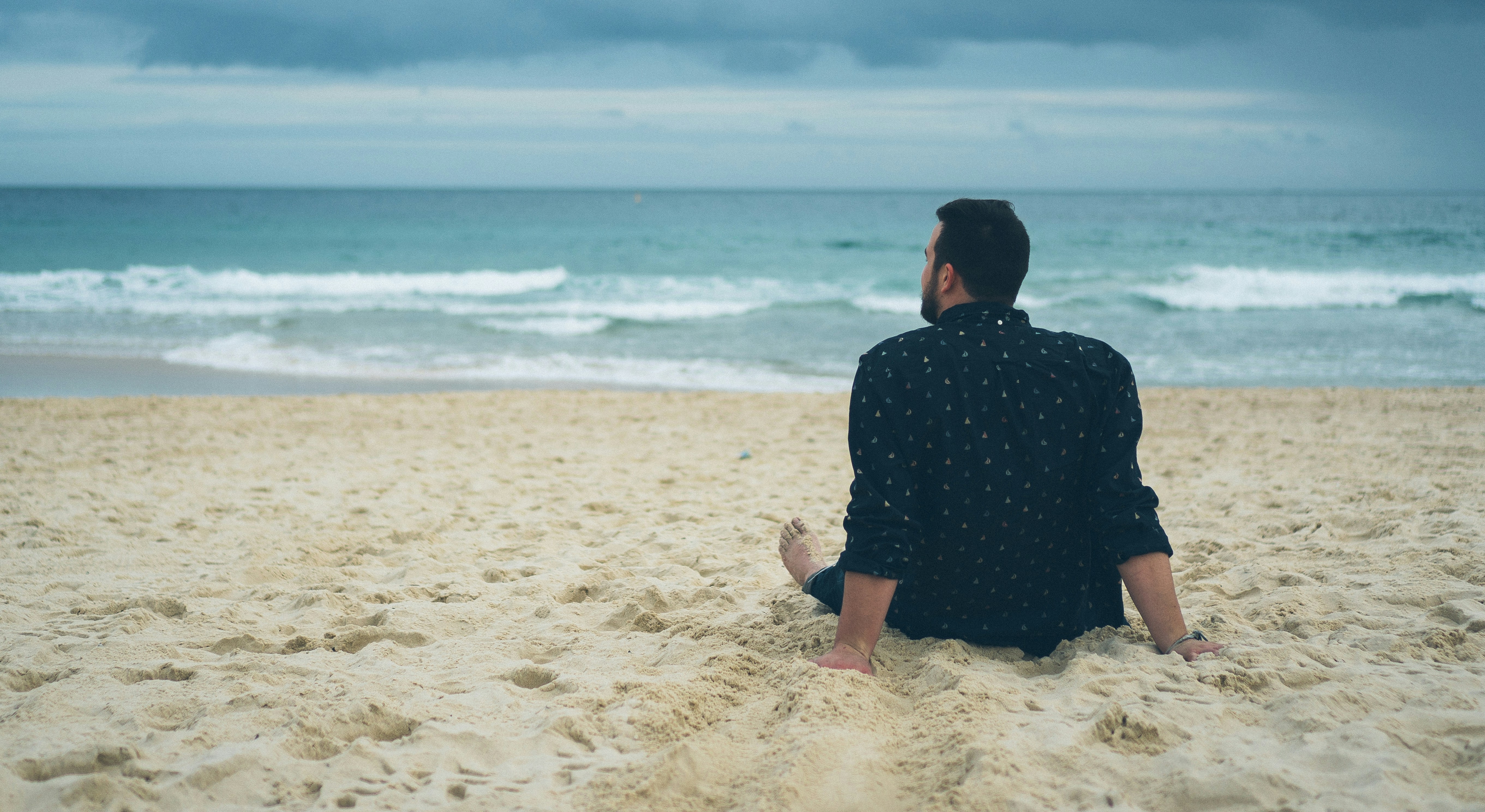 Man Sitting On Beach Sand Photo Free Image On Unsplash