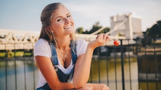 woman wearing white crew-neck shirt holding lollipop near bridge