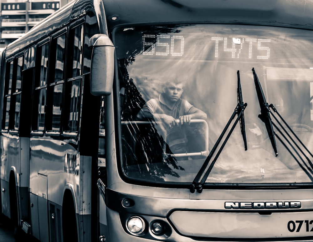 Foto in scala di grigi dell'uomo all'interno dell'autobus