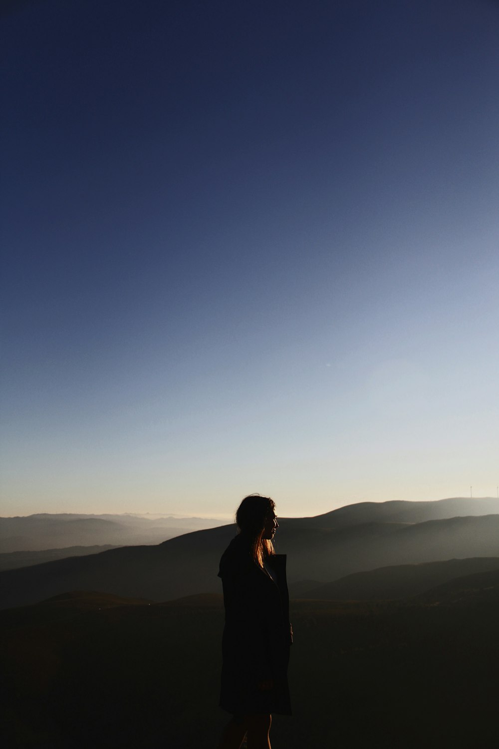 side view of woman on mountain under blue sky