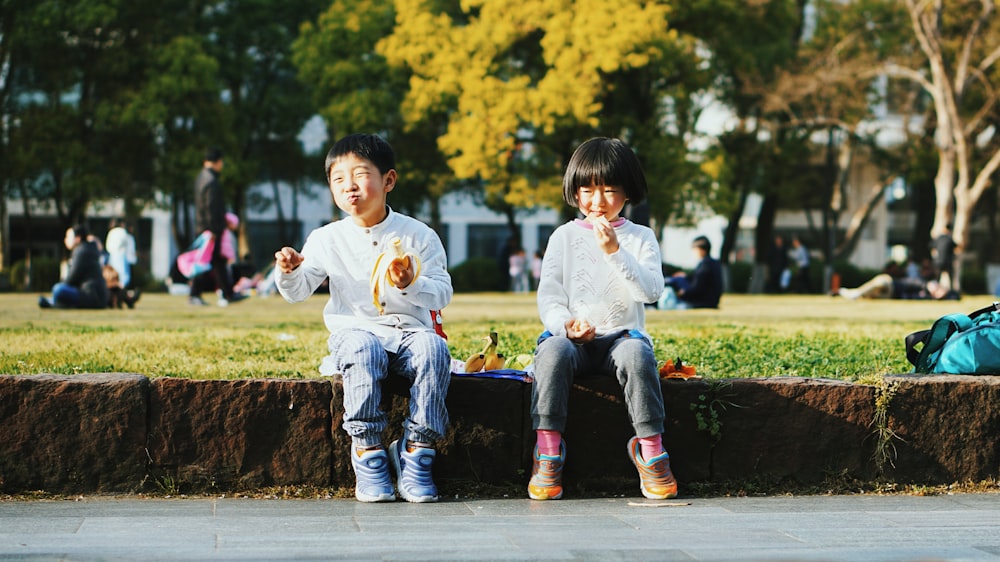two kids sitting on brown stone