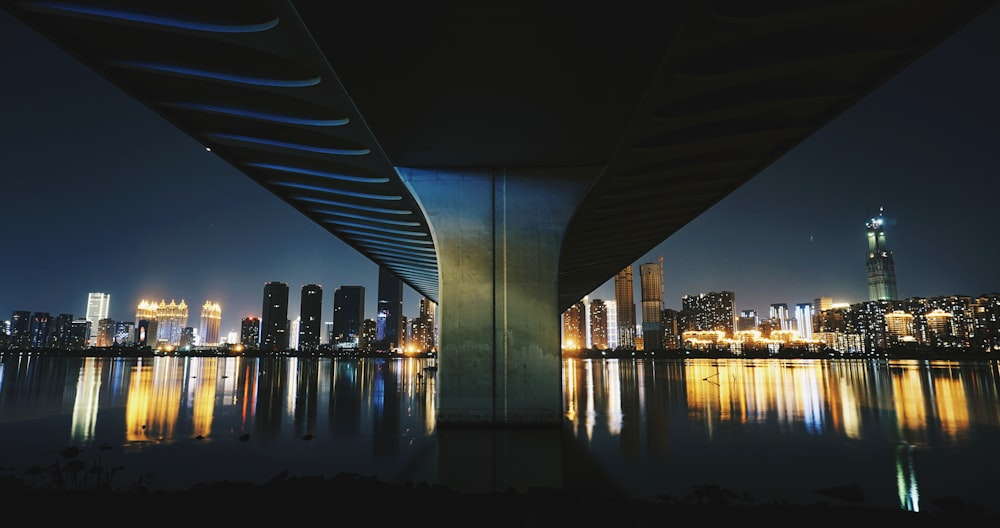 gray concrete bridge between city skyline during night time