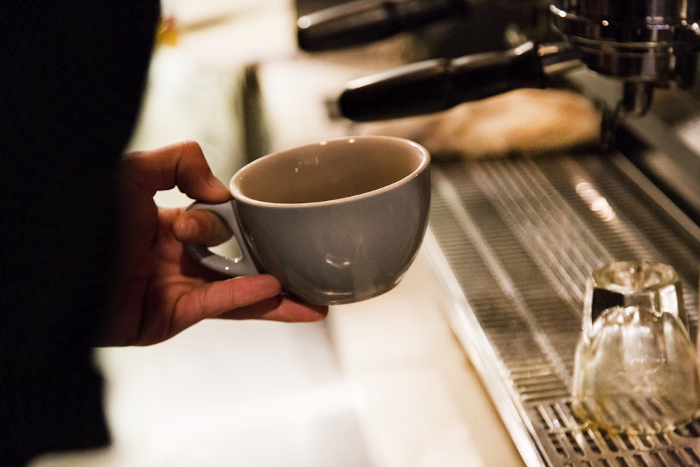 person holding gray ceramic mug