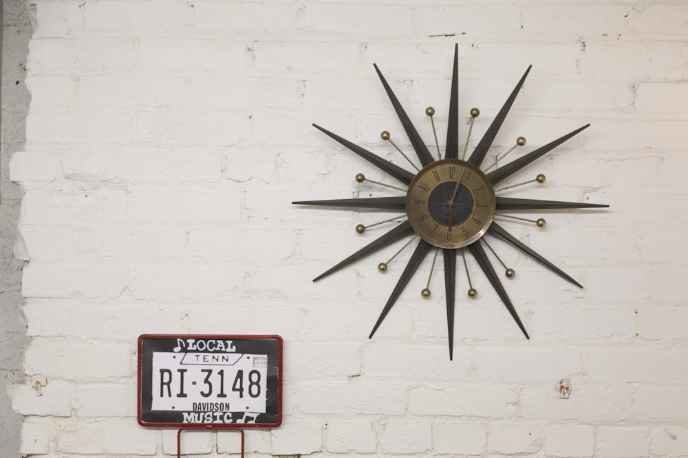 brown and black sun designed analog wall clock at 6:05