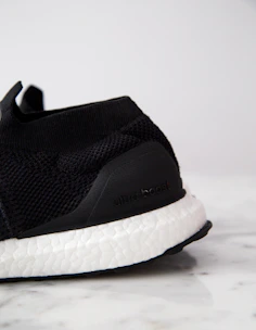 Close-up of sleek black and gold sneakers resting on a polished marble surface, highlighting premium materials and craftsmanship.