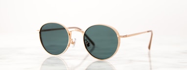 gold-colored framed hippie sunglasses on white surface