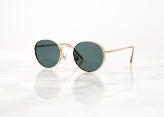 gold-colored framed hippie sunglasses on white surface