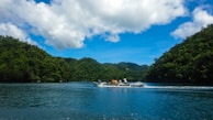 A tranquil scene at Kaptai Lake with a boat amidst scenic hills.