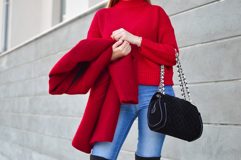 흰 벽 옆에 빨간 스웨터를 입은 여자