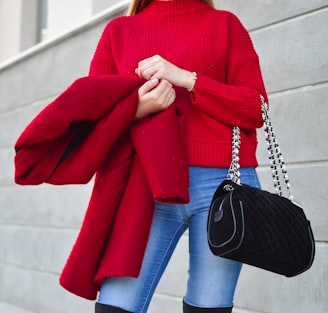 woman in red sweater beside white wall