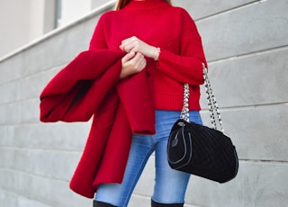 woman in red sweater beside white wall